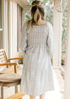 Back view of Model wearing a cream midi with blue floral, square neckline and smocked back.