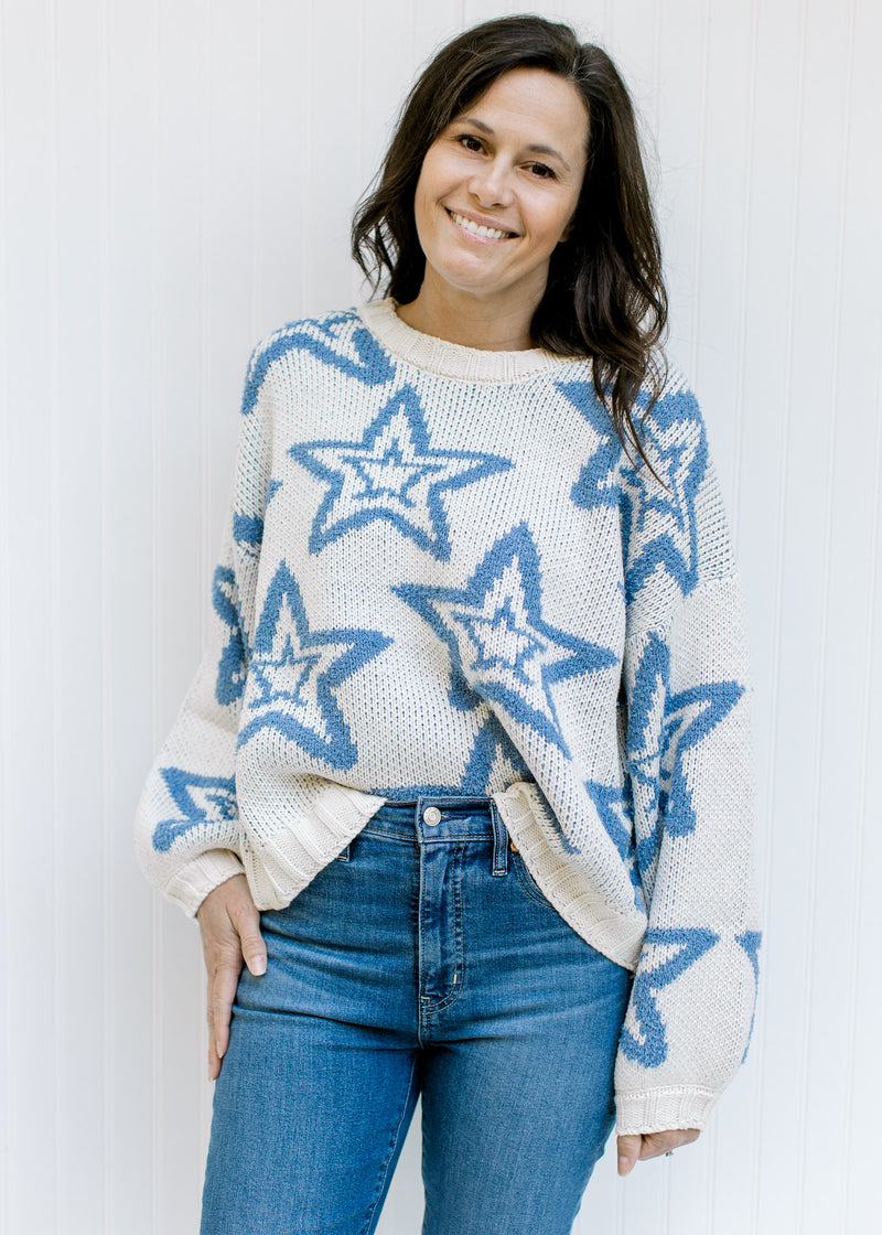 Model wearing a cream sweater with a blue star pattern, bubble long sleeves and a round neck. 