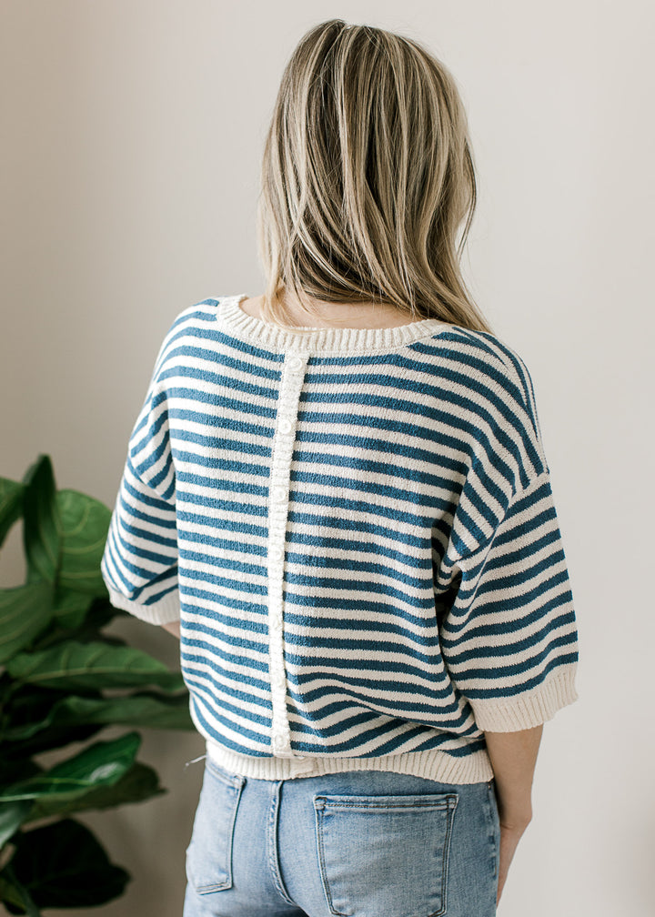 Back view of buttons down the back of a blue and cream striped knit sweater with short sleeves. 