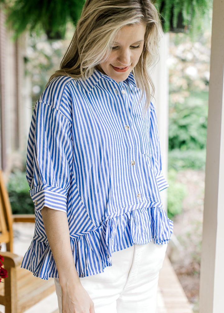 Model wearing a short sleeve blue and white striped top with a collar and working buttons.