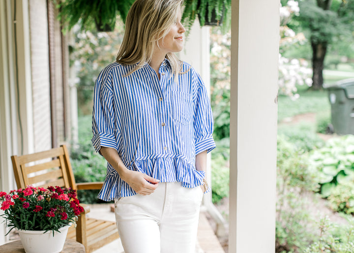 Model wearing a peplum blue and white striped top with a short sleeves and working buttons.