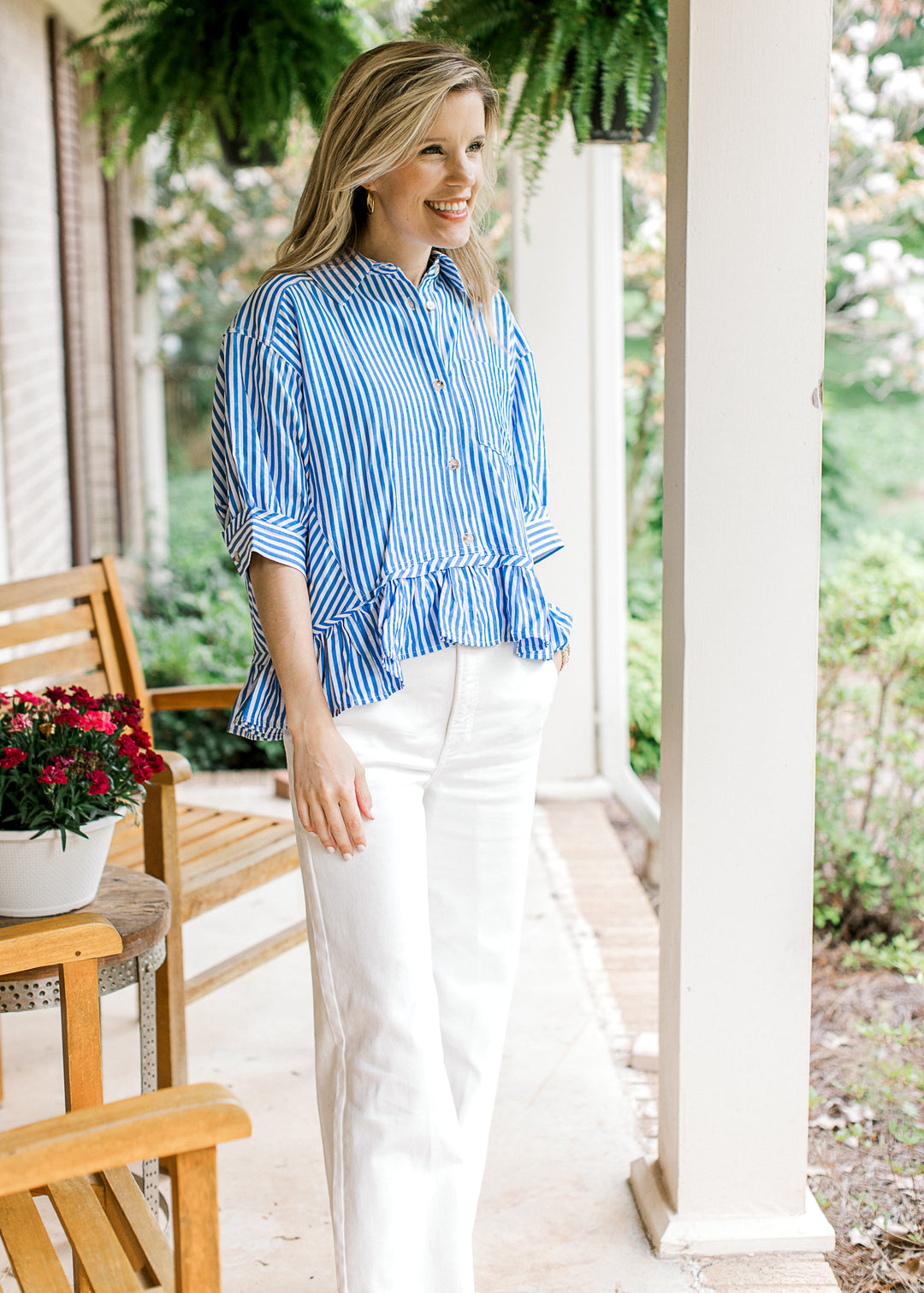 Model wearing white pants and  a short sleeve blue and white striped top with a collar. 