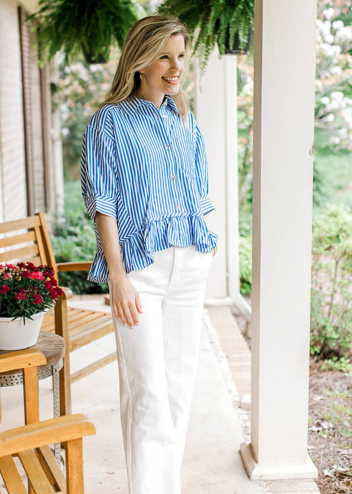 Model wearing white pants and  a short sleeve blue and white striped top with a collar. 
