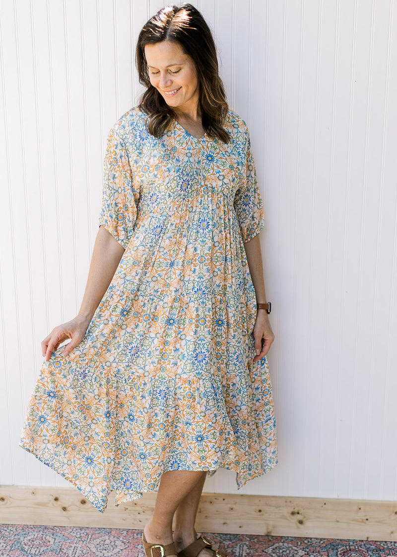 Model wearing a cream midi with blue, green and orange flowers and a v-neck.