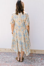 Back view of Model wearing a cream midi with blue, green and orange flowers and 3/4 sleeves. 