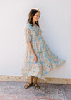 Model wearing a cream midi with blue, green and orange flowers and pockets.