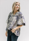 Model wearing a tan top with navy toile print, bubble short sleeves and ruched neck detail. 