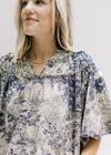 Close up of navy toile print on a tan top with a ruched v-neck and bubble short sleeves. 