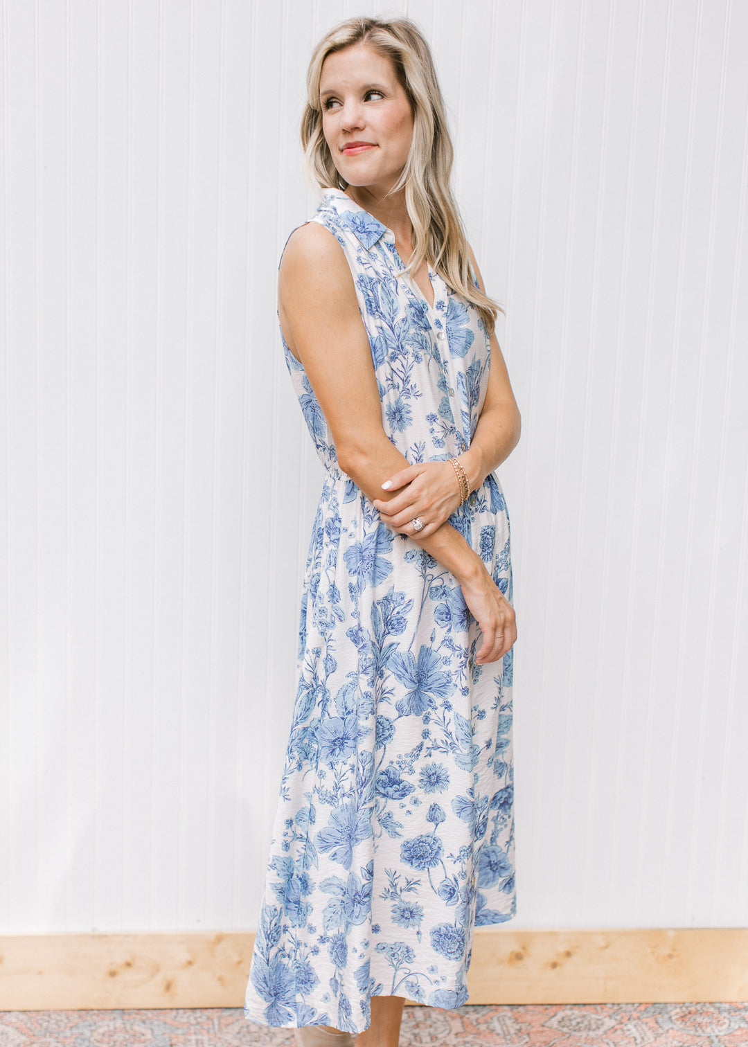 Model wearing a fully lined white dress with blue floral, button front and a collar. 