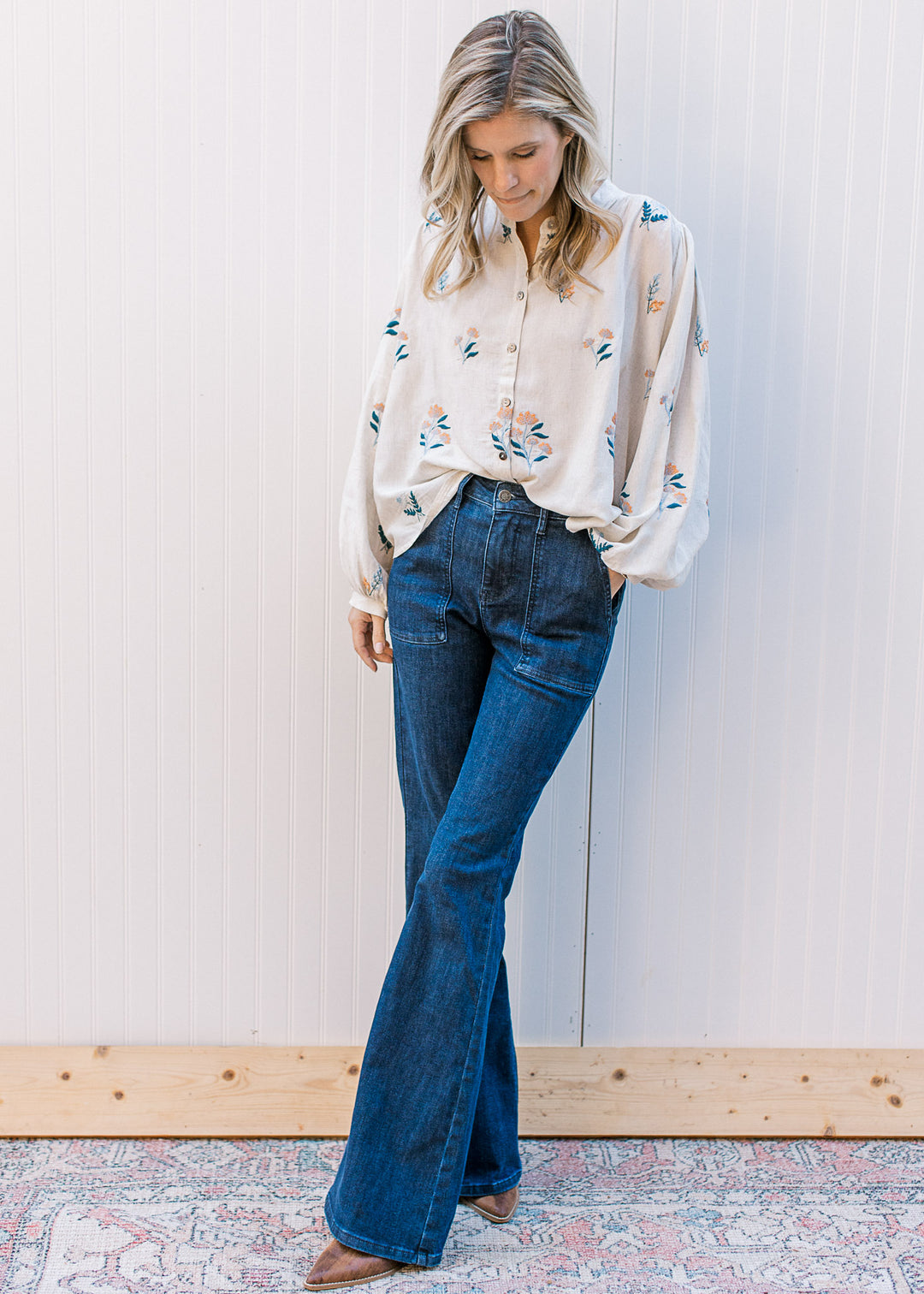 Model wearing an oatmeal button up with blue and yellow flowers with bubble long sleeves.