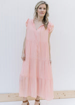 Model wearing a blush tiered midi with layered ruffle cap sleeves and v-neck with a tie.