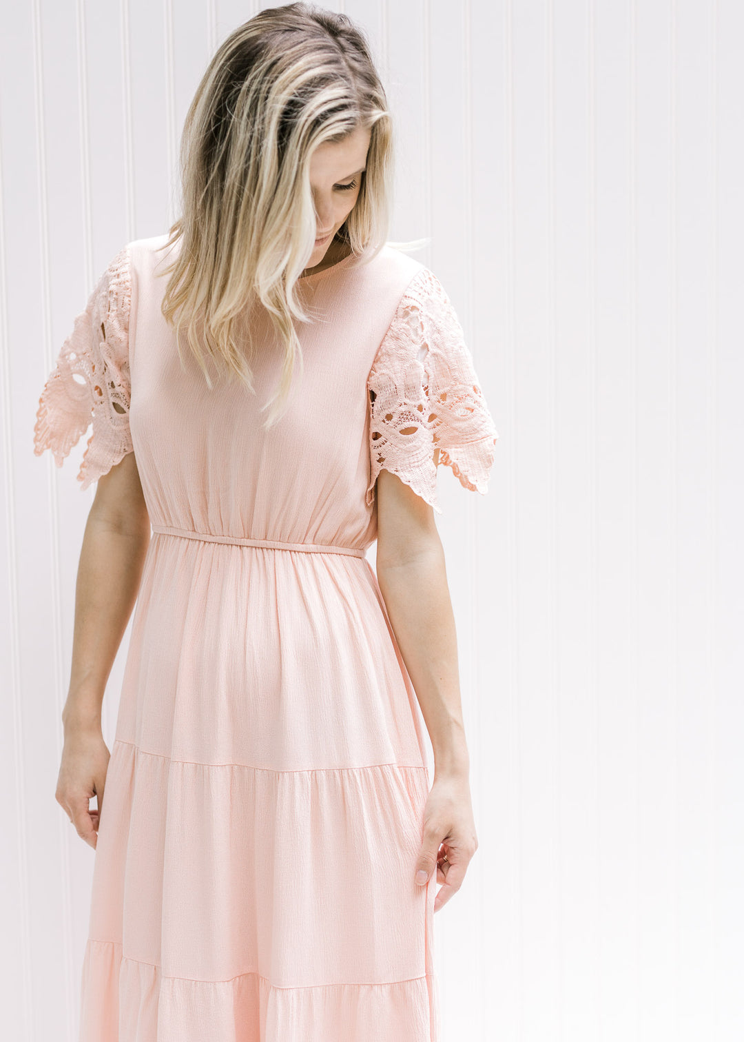 Model wearing a pale pink maxi dress with an elastic waist and cutwork lace short sleeves. 