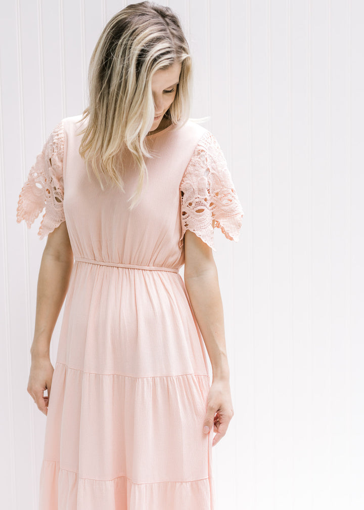 Model wearing a pale pink maxi dress with an elastic waist and cutwork lace short sleeves. 