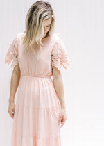 Model wearing a pale pink maxi dress with an elastic waist and cutwork lace short sleeves. 