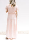Back view of Model wearing a pale pink maxi dress with an elastic waist and cutwork lace sleeves. 