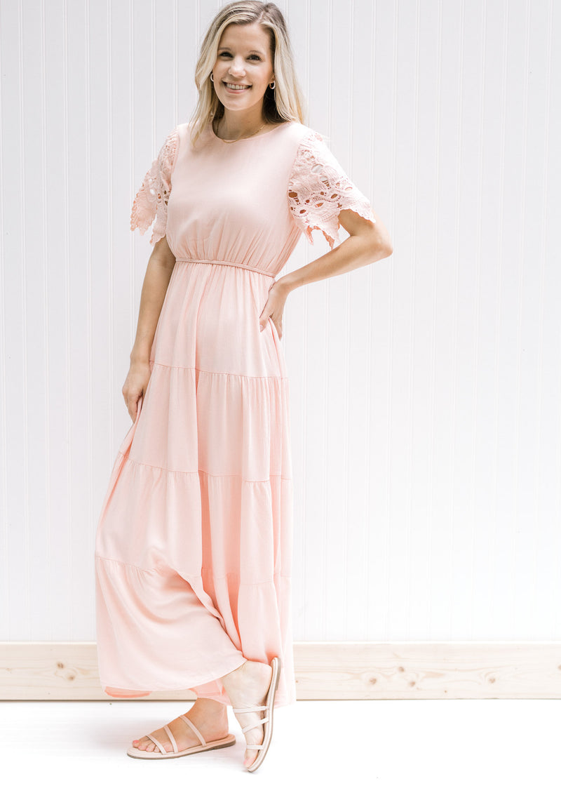 Model in a pale pink maxi dress with an elastic waist and lace short sleeves with scalloped edge. 