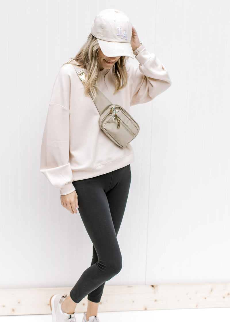Model wearing a hat and leggings with a  blush sweatshirt with long sleeves and a round neck. 