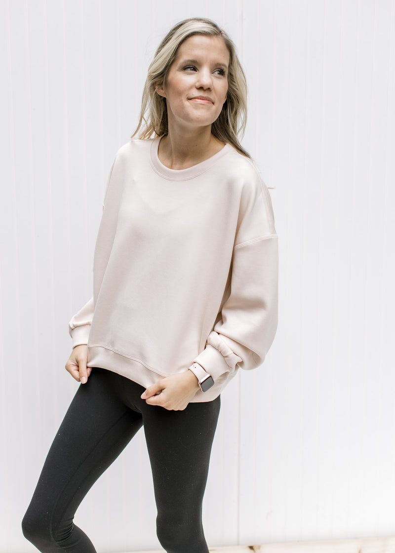 Model wearing leggings with a blush slightly cropped sweatshirt with long sleeves and a round neck. 