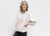 Model wearing a blush lightweight, slightly cropped sweatshirt with long sleeves, and a round neck. 