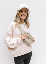 Model wearing a hat with a blush slightly cropped sweatshirt with long sleeves and a round neck. 