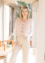 Model wearing a blush ultra soft sweater vest with embroidered flowers, v-neck and button front. 