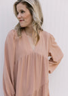 Close up of v-neck and pleated shoulders on a blush long sleeve dress hitting just above the knee.