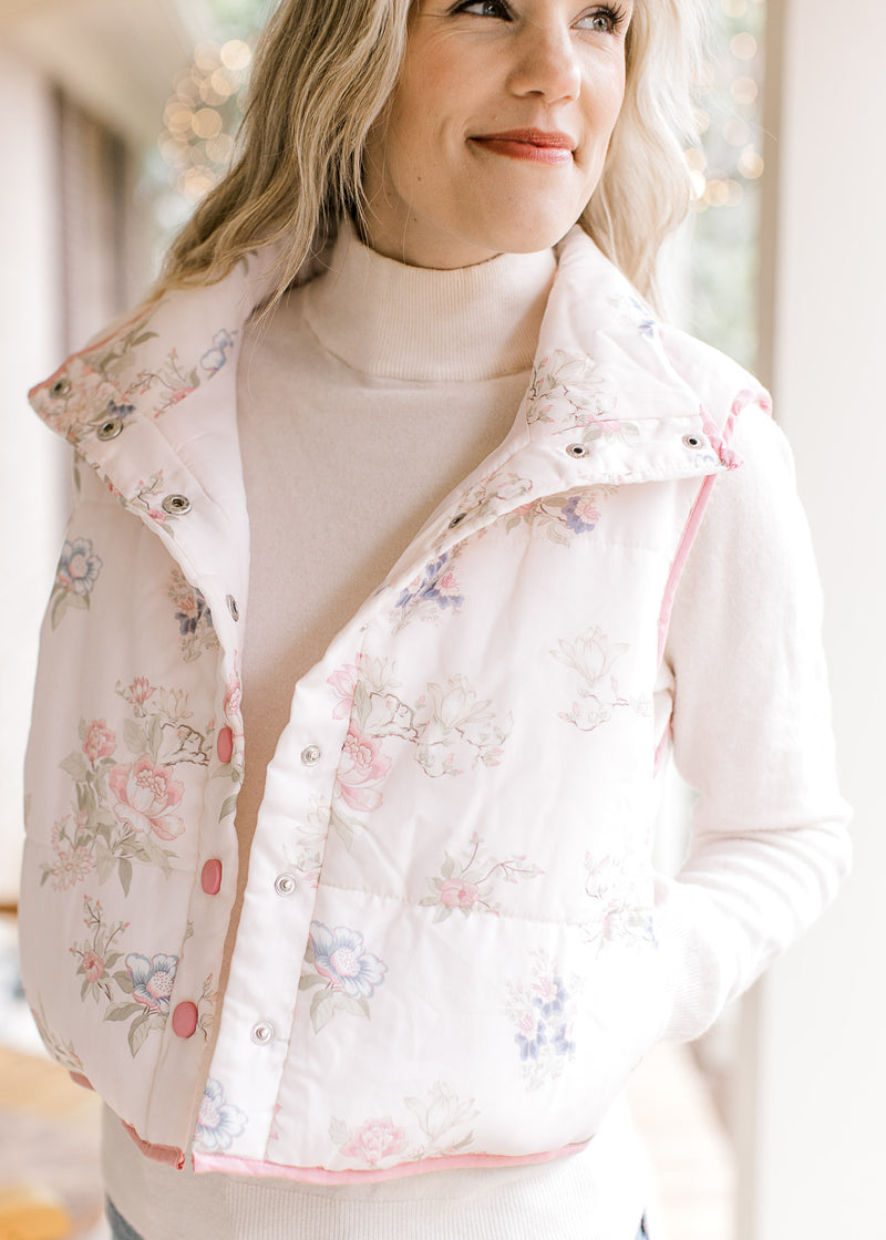 Close up of pink snap closure buttons and a mock neck on a pale pink puffer vest with flowers.