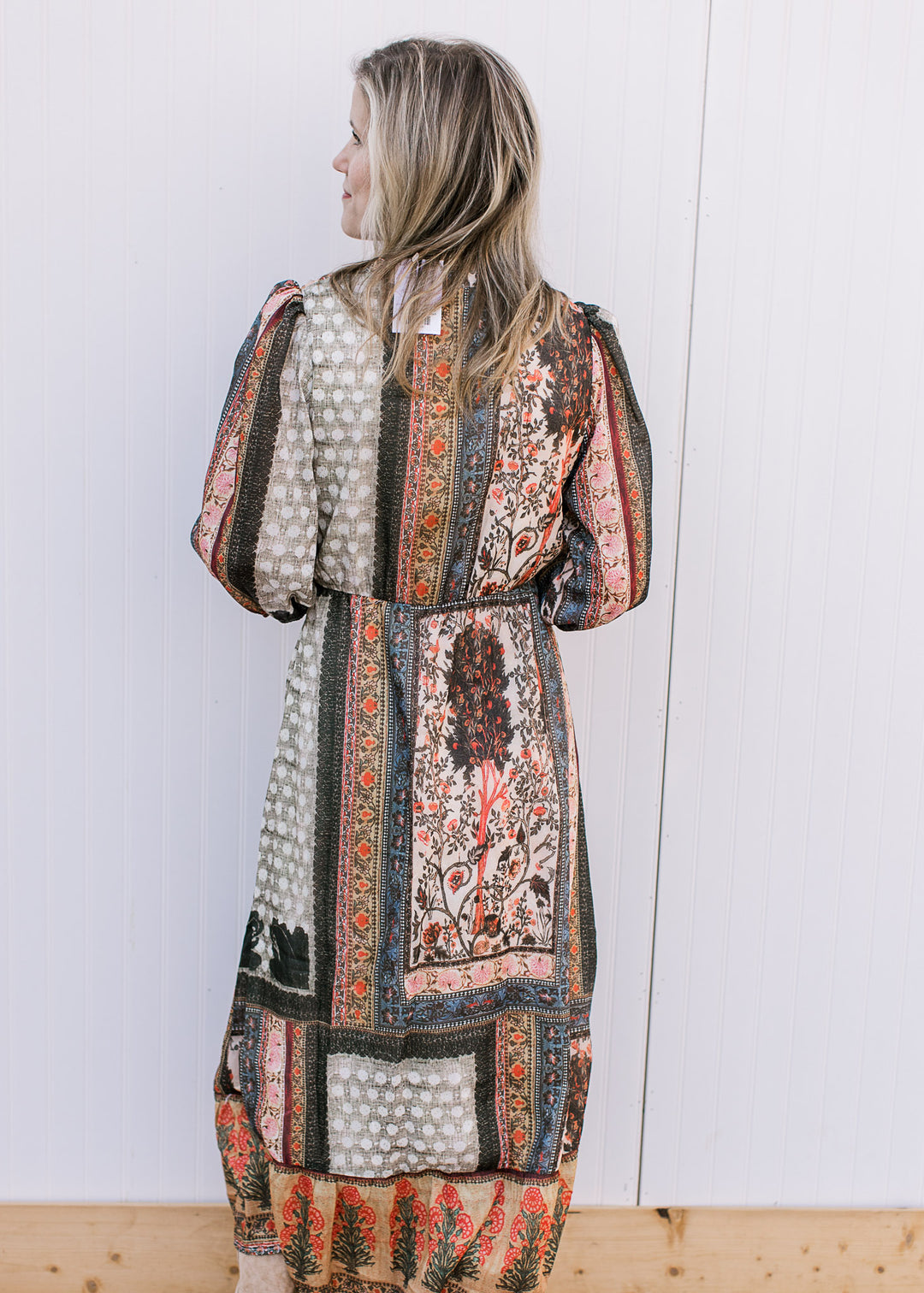 Back view of Model wearing a bohemian patterned midi with a v-neck, 3/4 sleeves and elastic waist.