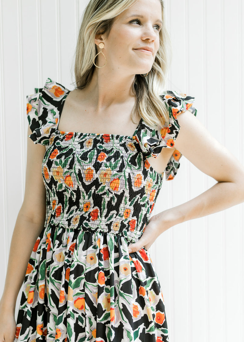 Close up of smocked bodice on a sleeveless black dress with a vibrant floral pattern.
