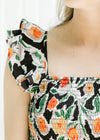Close up of layered ruffles and square neck on a black sleeveless dress with a floral pattern.