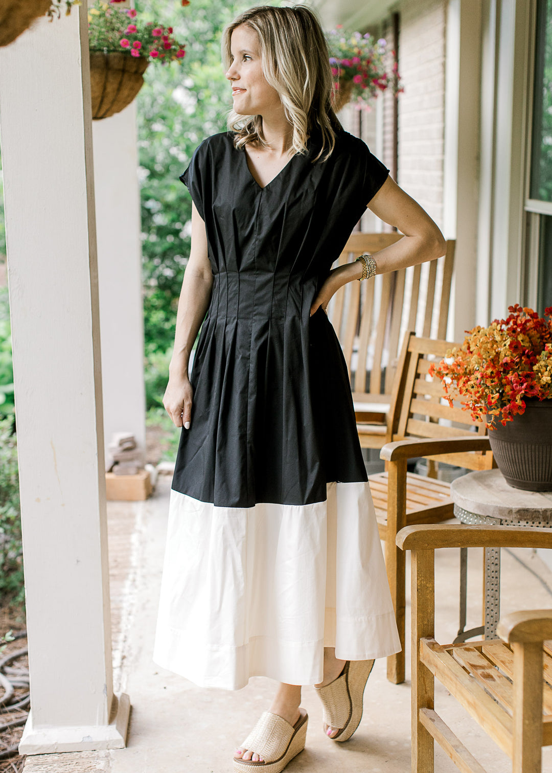 Model wearing a black and cream colorblock midi with cap sleeves and pleating at the waist. 