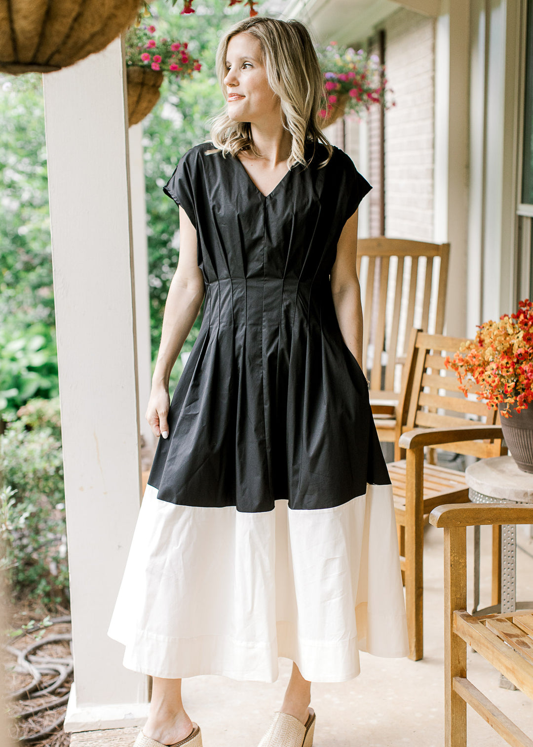 Model wearing a black and cream colorblock midi with cap sleeves, pockets and pleated waist. 