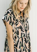 Close up view of Model wearing a black button up midi dress with tiers and short sleeves.