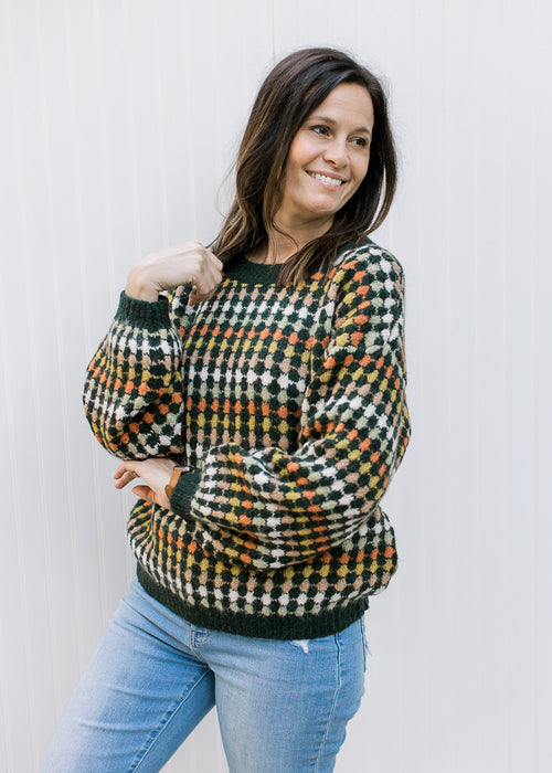 Model wearing a navy sweater with fall colored dots, bubble long sleeves and a round neck.