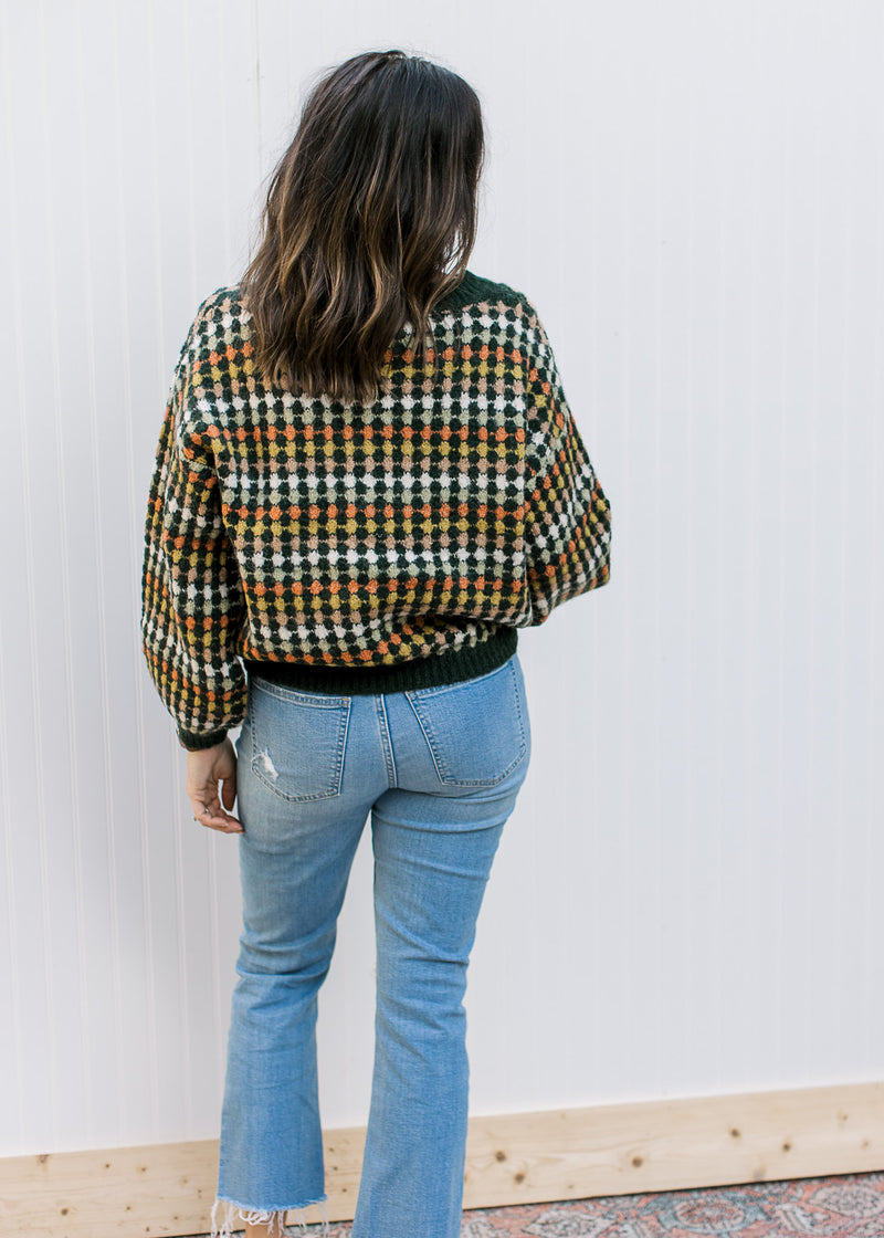 Back view of Model wearing a navy sweater with fall colored dots and bubble long sleeves.