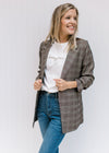 Model wearing jeans and a tweed jacket over a white tee with bonjour embroidered in tan. 