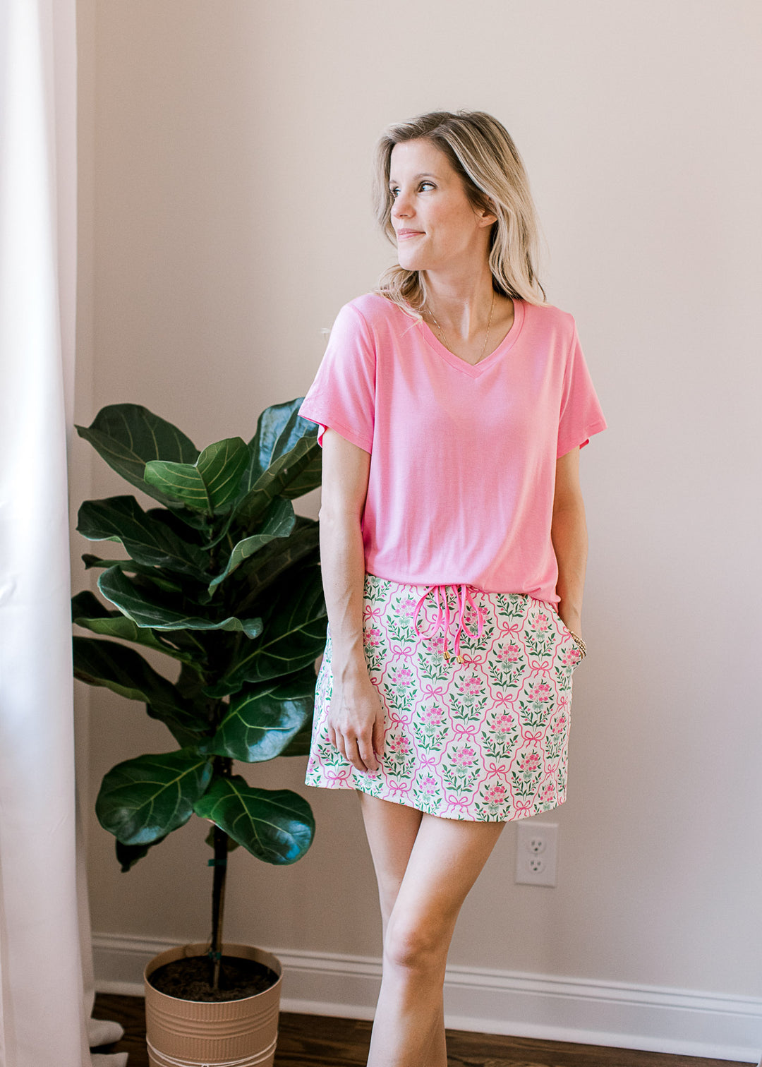 Model wearing an off white skort with pink and green floral, elastic waist and built-in shorts.