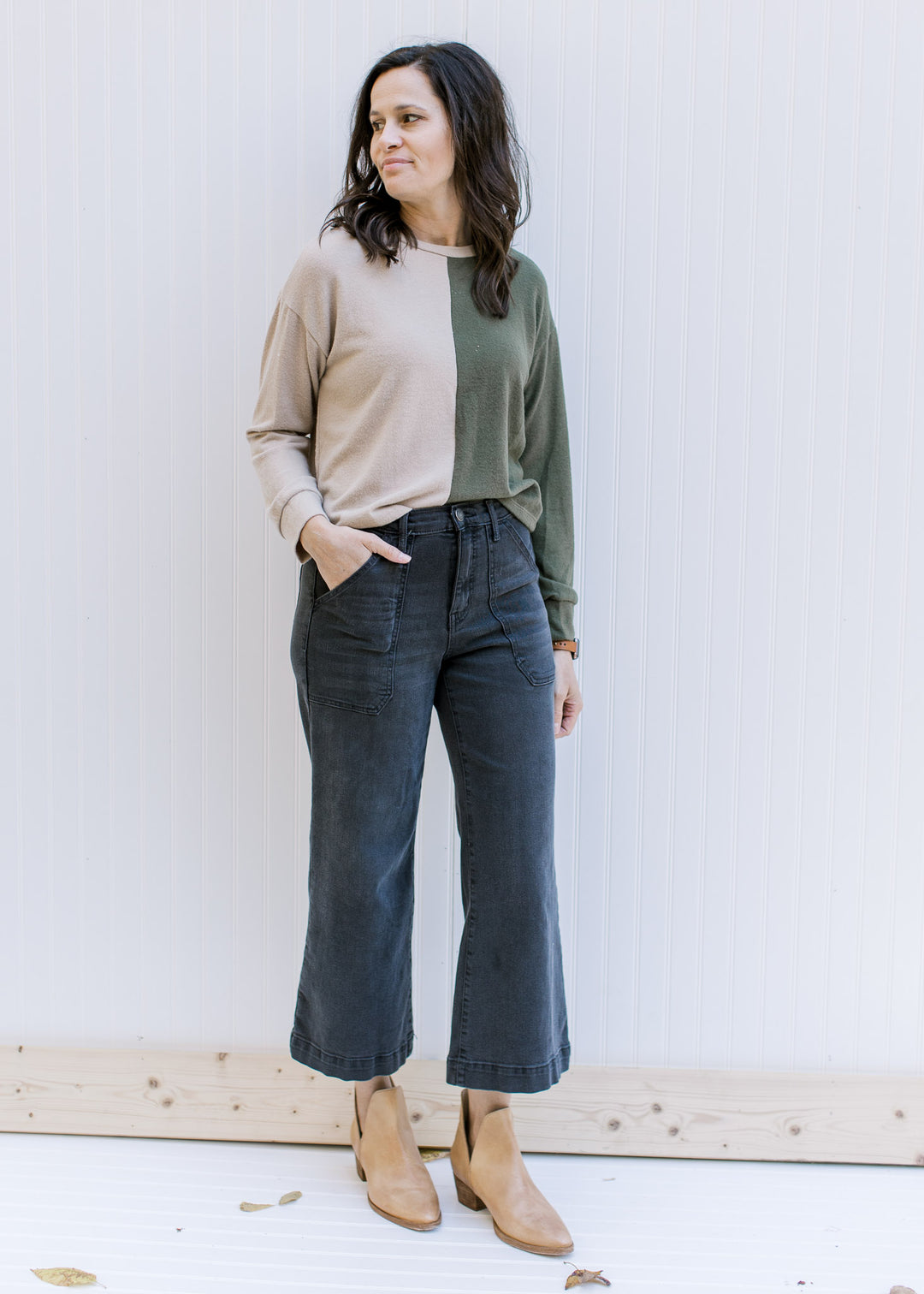 Model wearing jeans and mules with a camel and forest green color block sweater with long sleeves. 