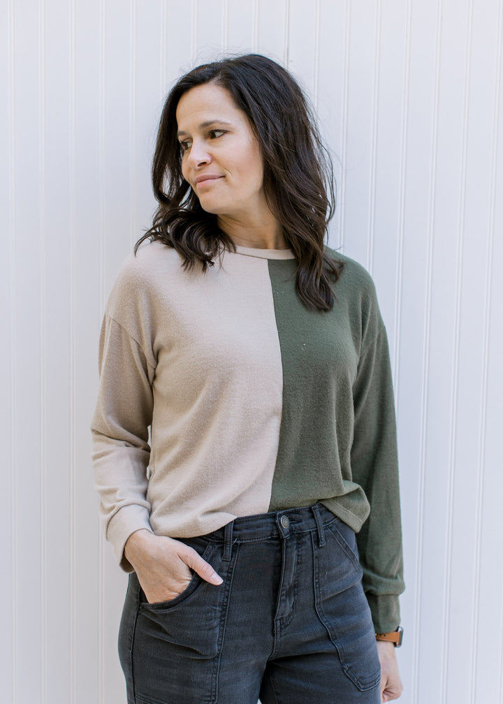 Model wearing a camel and forest green color block sweater with a split detail and long sleeves. 