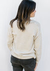 Back view of Model wearing a cream and tan sweater with a black bow and long sleeves.