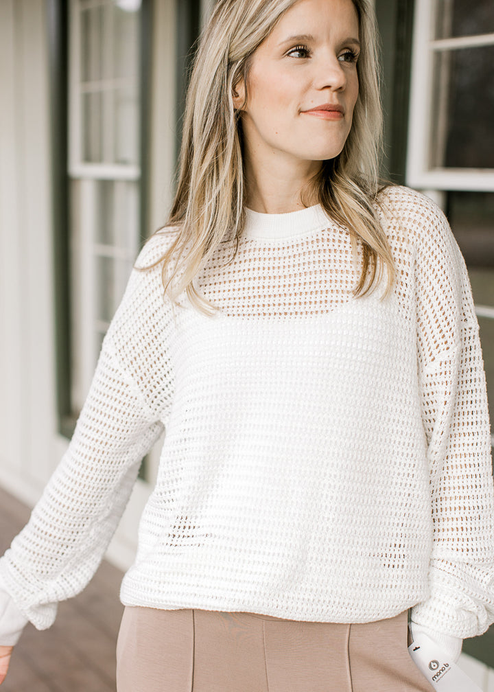 Model wearing a white, open-knit top with a round neck, long sleeves and ribbed neck, cuff and hem. 