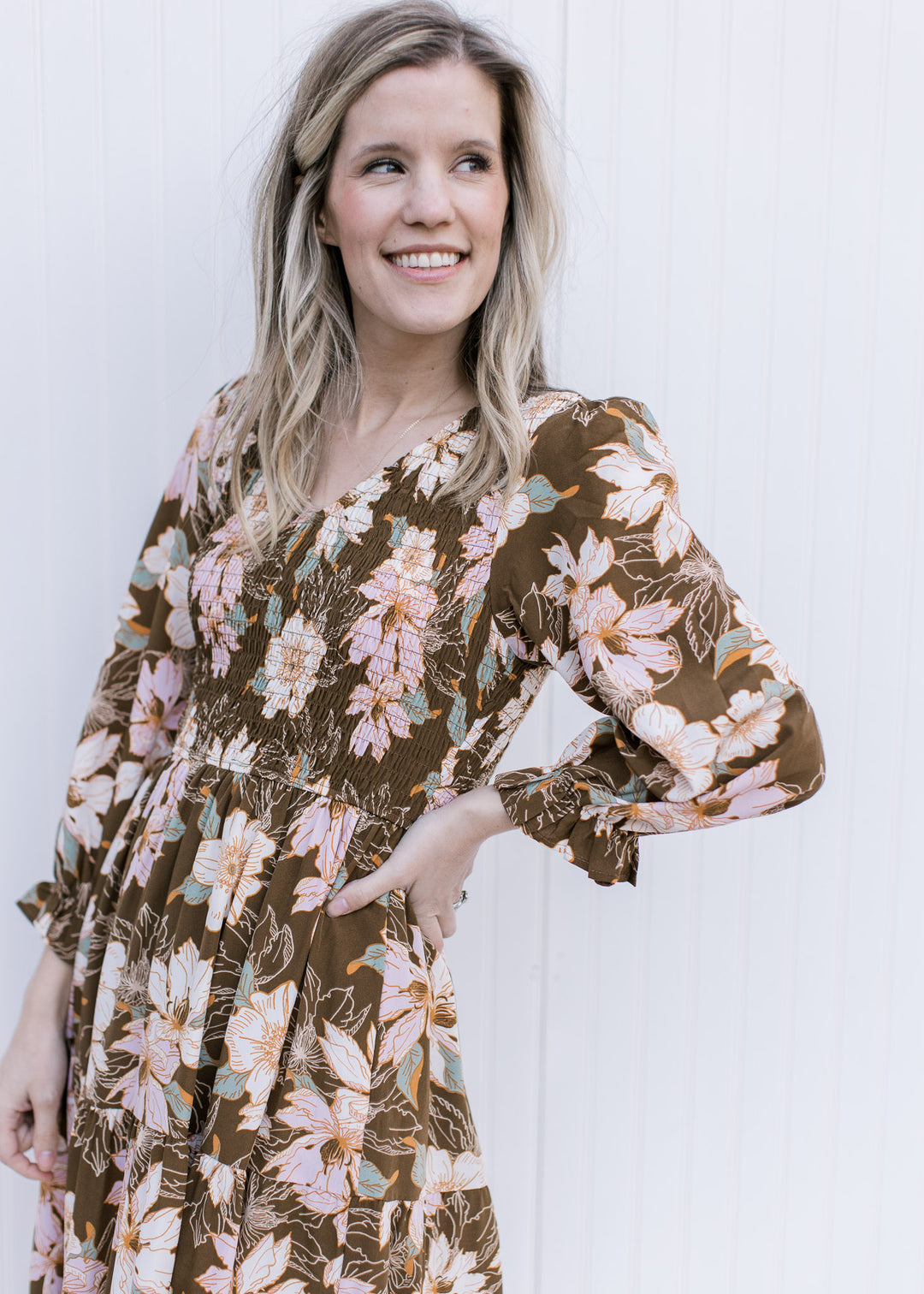 Model wearing a brown maxi with a pink, cream and green floral pattern and a smocked bodice.