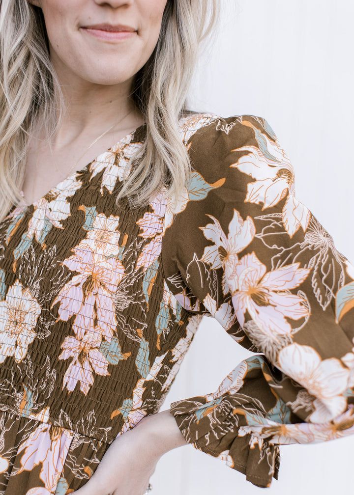 Close up of smocked bodice and v-neck on a brown maxi with pink, cream and green floral. 