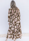 Back view of Model wearing a brown maxi with a pink, cream and green floral pattern and 3/4 sleeves.
