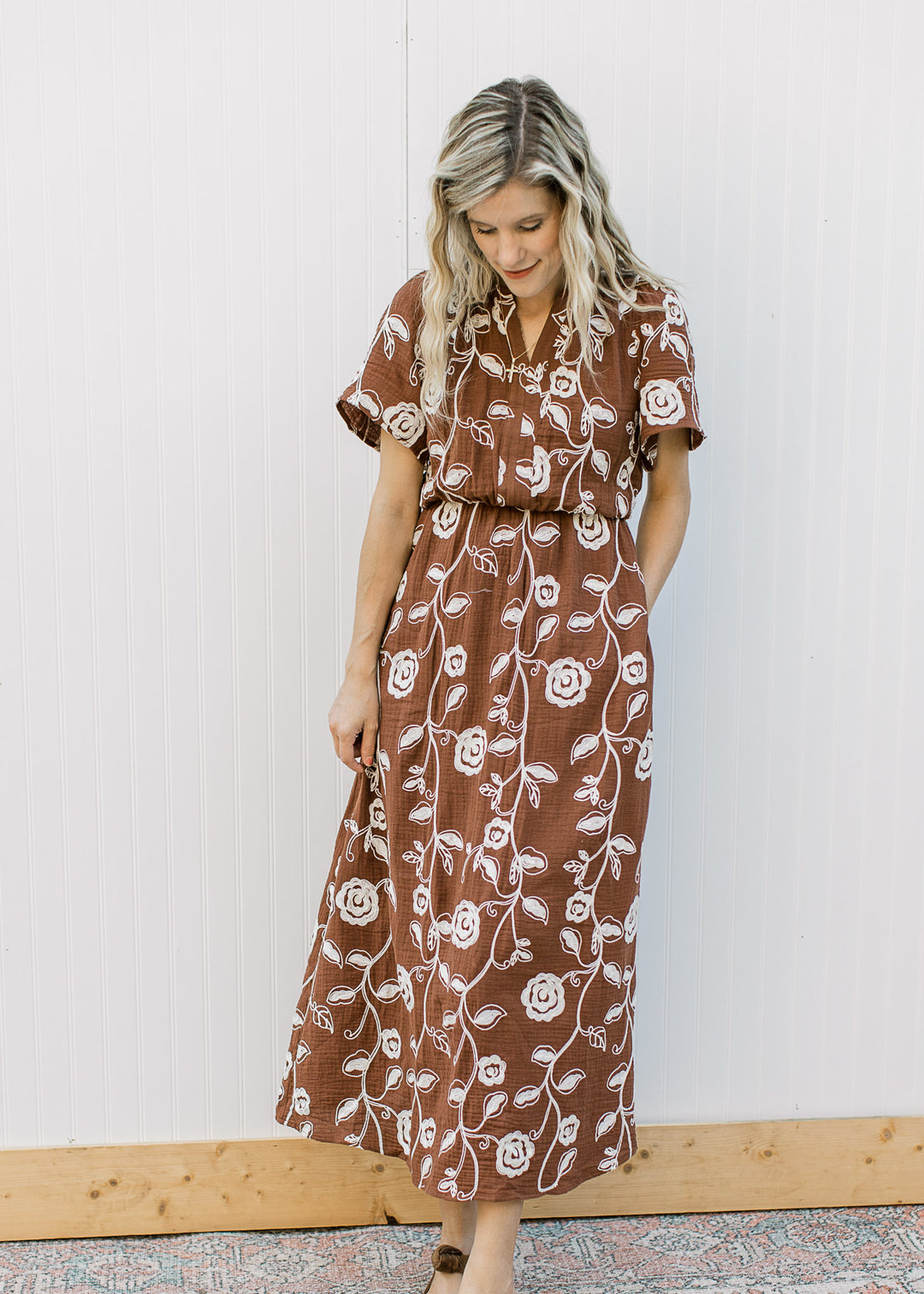 Model wearing a brown midi with embroidered cream floral, v-neck and short sleeves.
