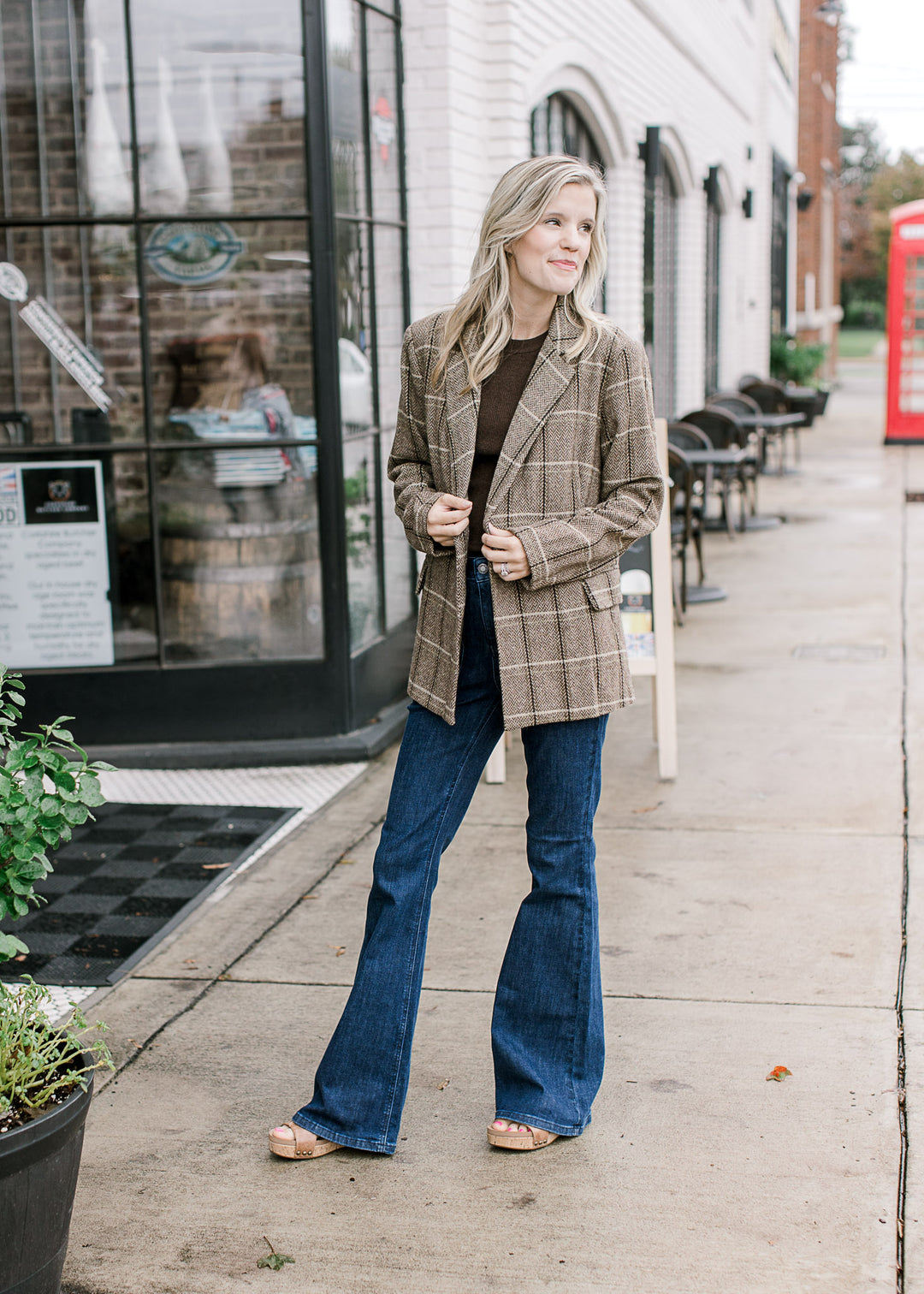 Model wearing a classic brown and cream plaid blazer with double-breasted front and faux pockets. 