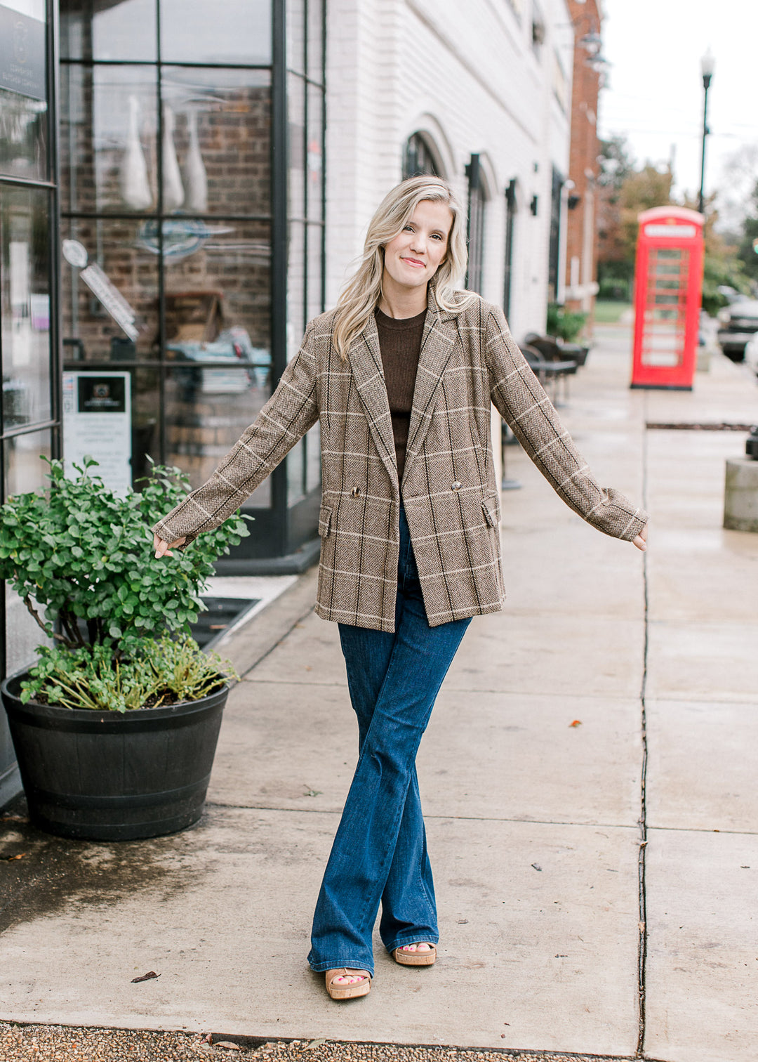 Model wearing a brown top and a brown and cream plaid blazer with double-breasted front.