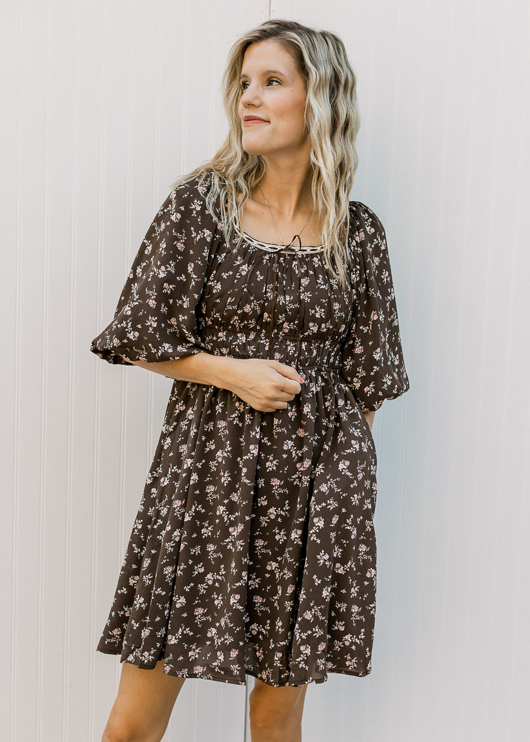 Model wearing a brown above the knee dress with elastic waist, 3/4 sleeves and pockets. 