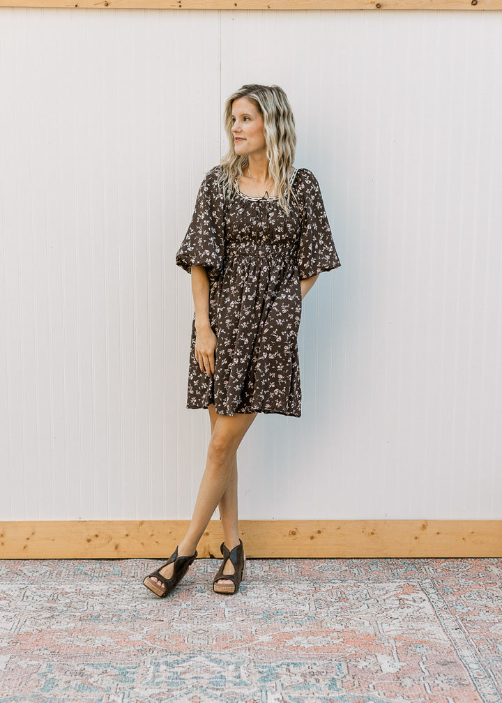 Model wearing wedges and a brown above the knee dress with elastic waist, 3/4 sleeves and pockets. 