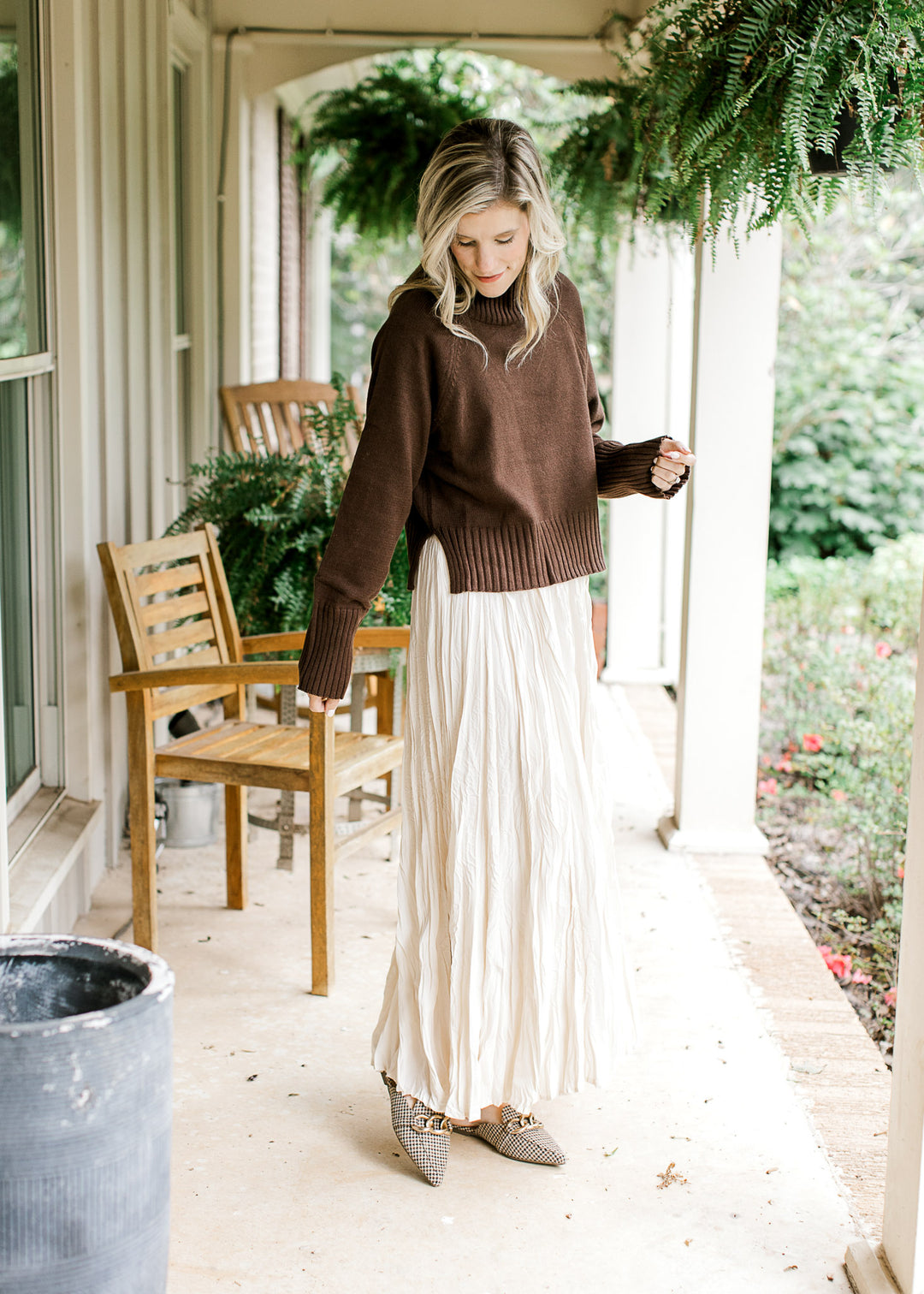 Model wearing a cream maxi and a brown sweater with a mock neck and long sleeves. 